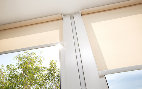 a photo of peach coloured roller blinds, fitted closely to a window taken from below