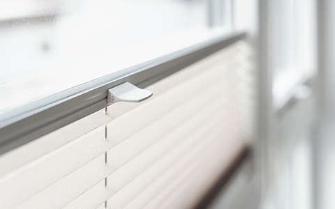 a close up of white pleated blinds on a window