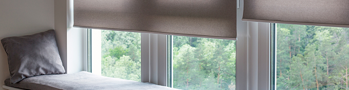 a set of roller blinds installed on a window next to a cushioned bay area
